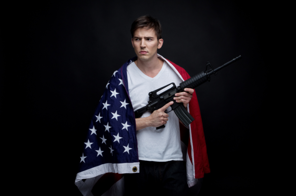 man wearing american flag holding an AR-15 rifle